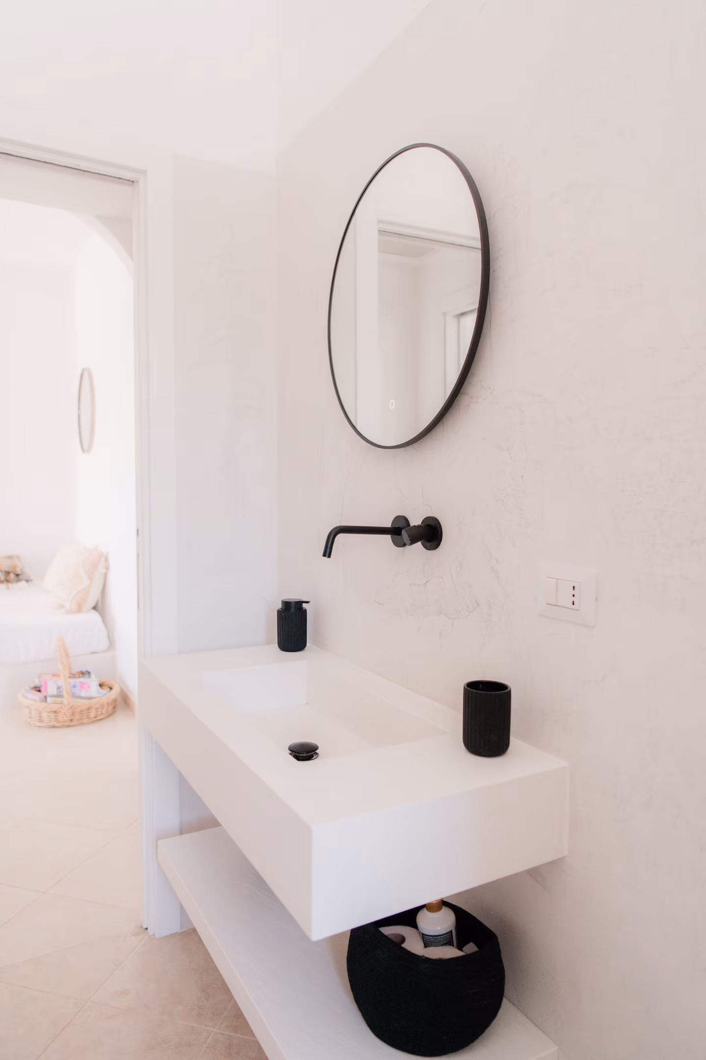 Minimalist bathroom with a microcement basin and a round LED mirror