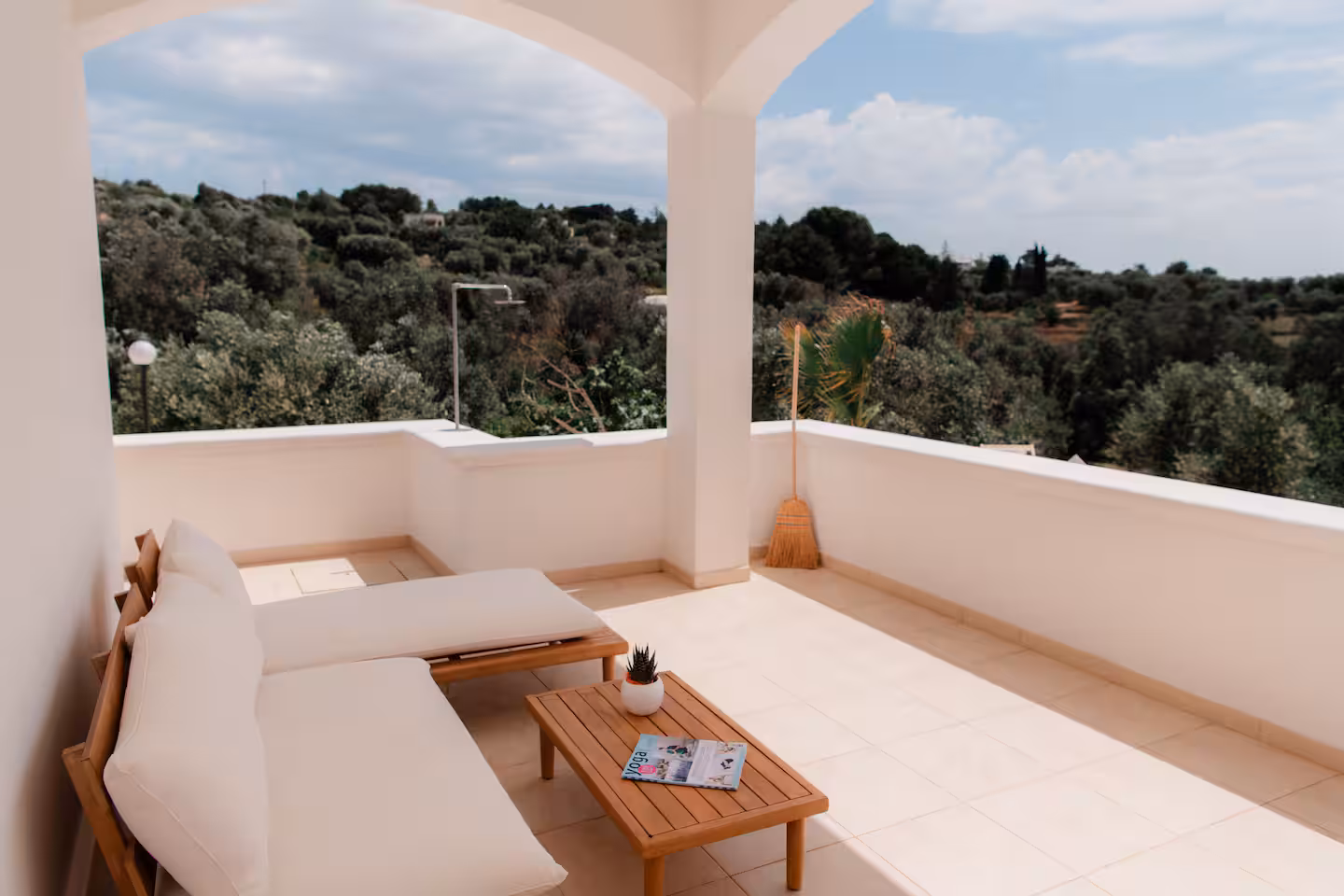 Covered loggia with a lounge sofa and an arched view over the olive grove