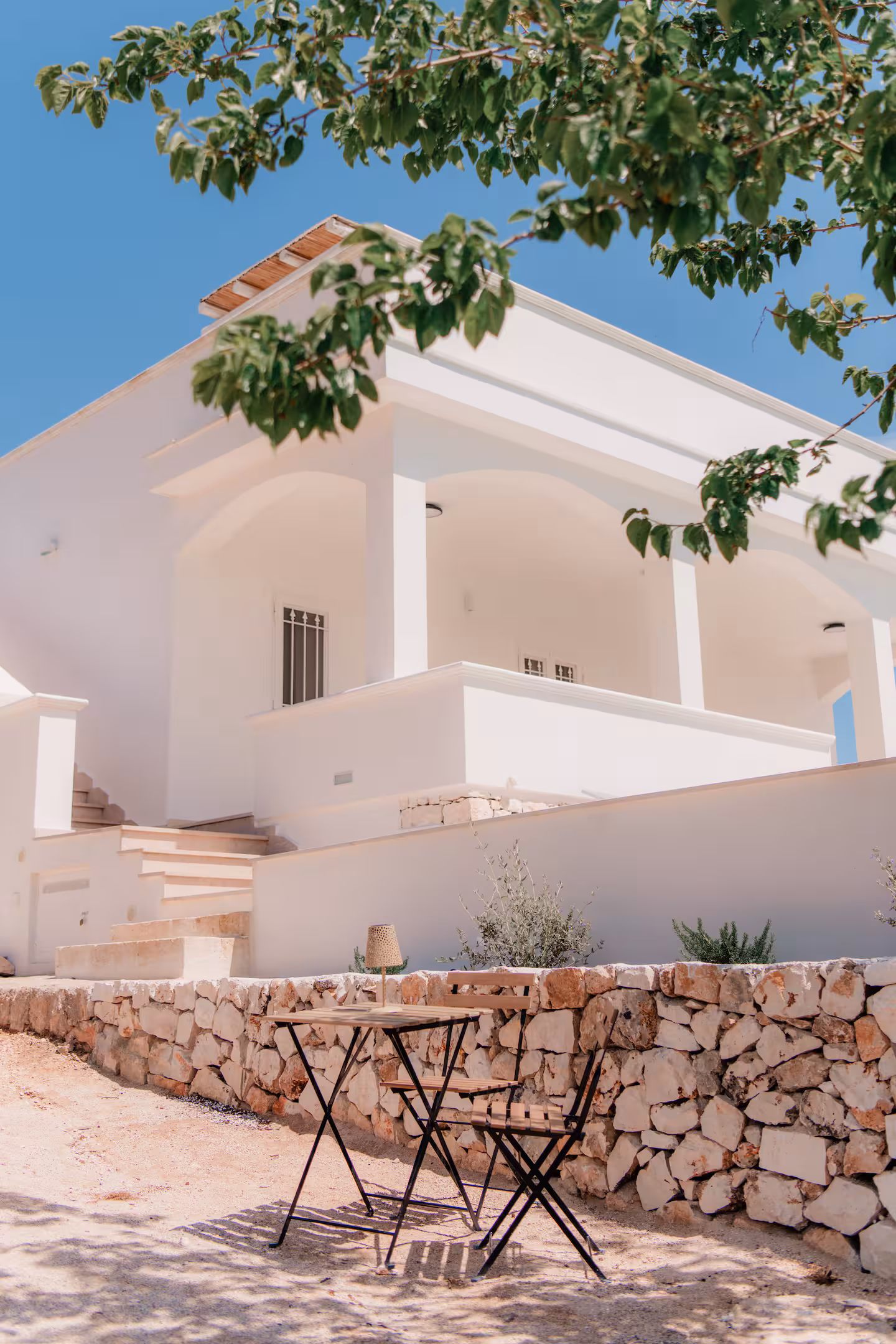 Whitewashed villa façade with an arched loggia and an olive tree
